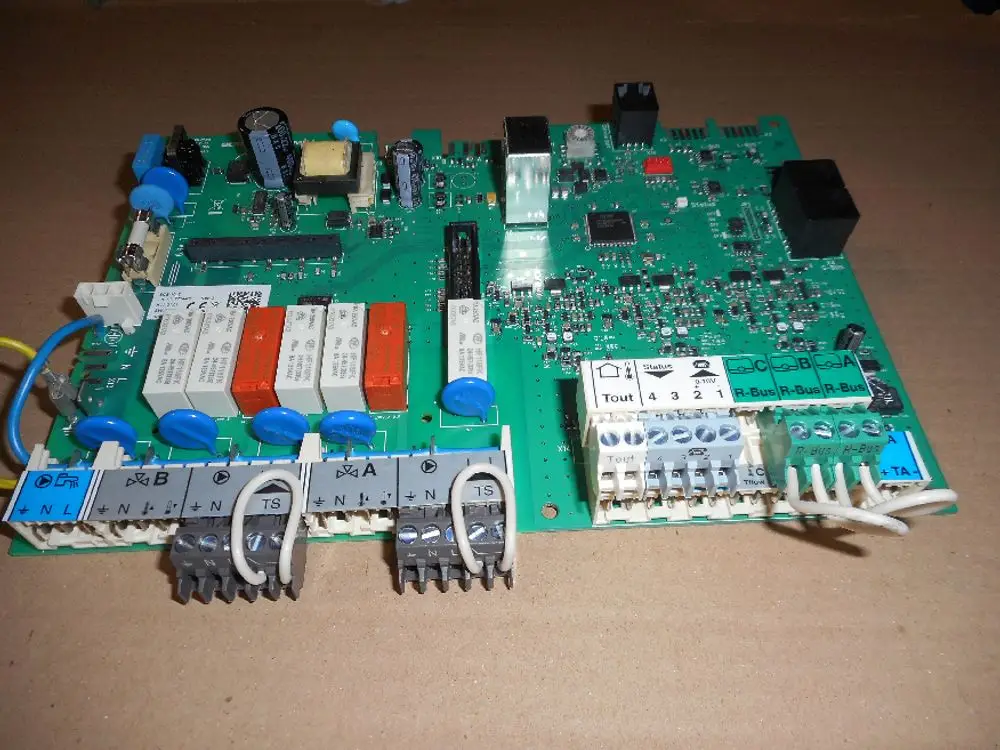 Platine von Remeha mit mehreren Relais, Kondensatoren und Anschlüssen. Die Leiterplatte enthält verschiedene elektronische Komponenten zur Steuerung.